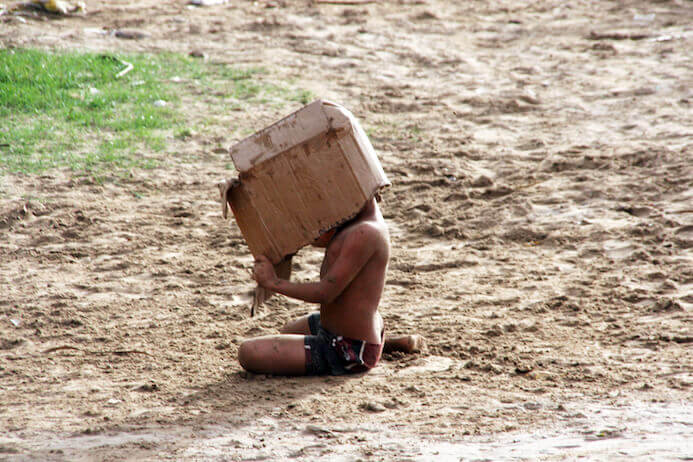 fotografia portfolio tips - bambino che gioca con una scatola sulla sabbia in Venezuela